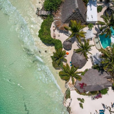 Breathtaking aerial view of a tropical beach resort in Zanzibar with turquoise waters and palm trees.