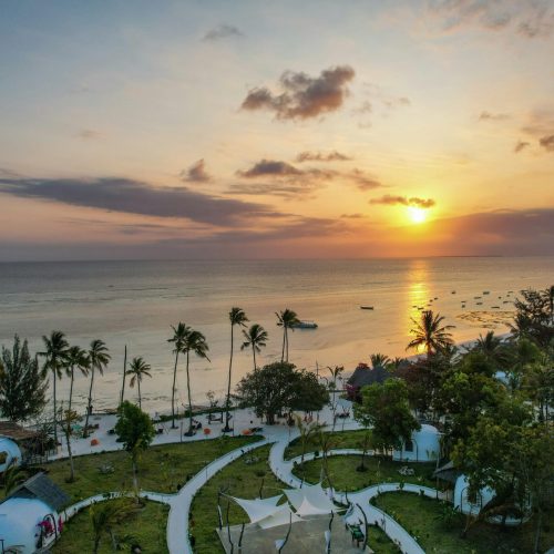 A breathtaking aerial view of Kizimkazi Beach at sunset, showcasing vibrant skies and serene waters in Tanzania.