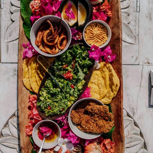 A colorful platter featuring diverse local Zanzibar dishes and flowers.