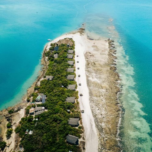 Stunning aerial photo of a coastal island surrounded by clear turquoise waters.