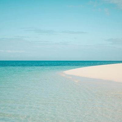Pristine white sandy beach with clear turquoise ocean in Zanzibar, Tanzania, under a bright summer sky.