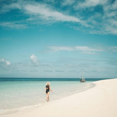 A woman enjoys a serene walk on a pristine beach in Zanzibar, Tanzania.